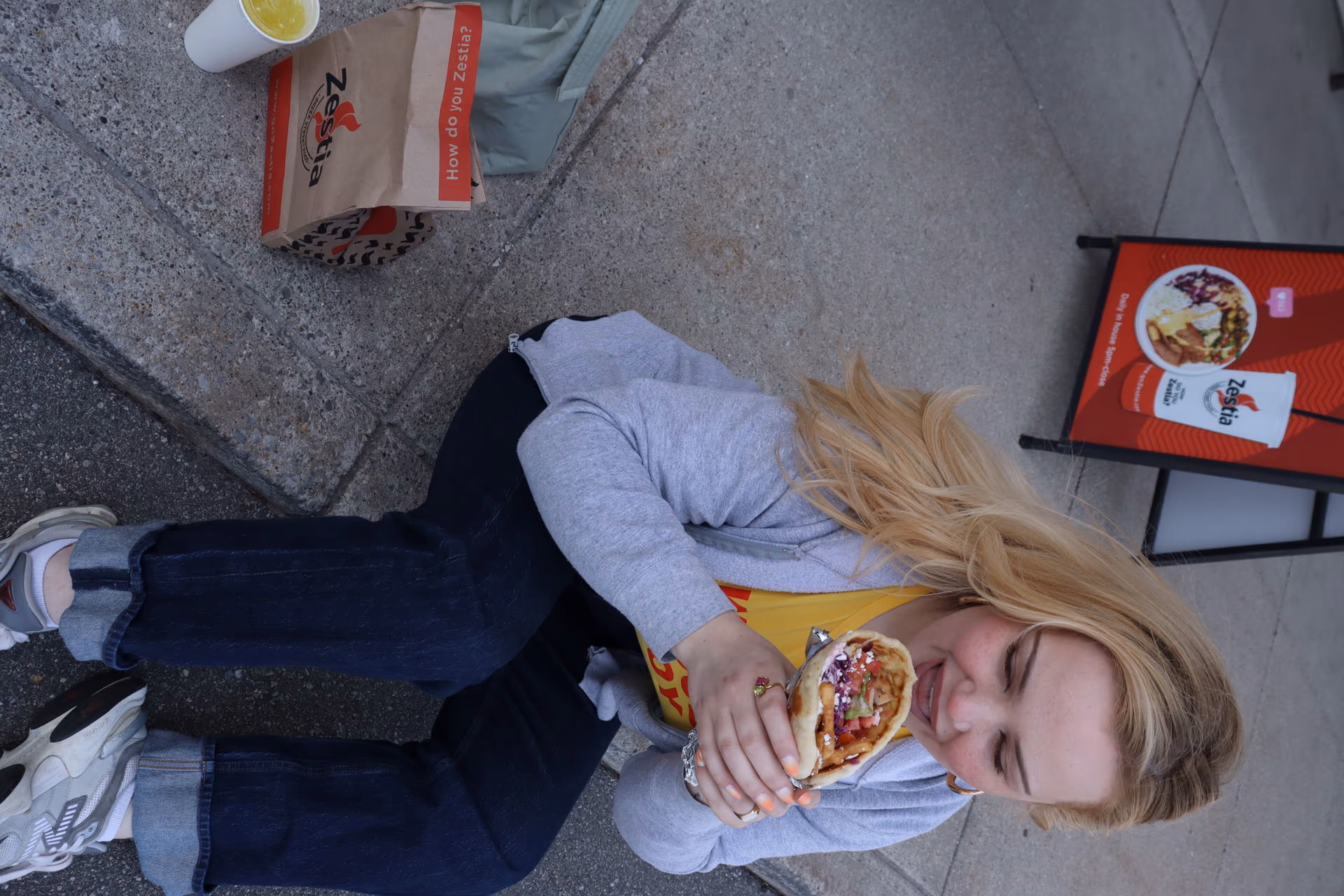 A lady enjoying a Zestia gyro outside